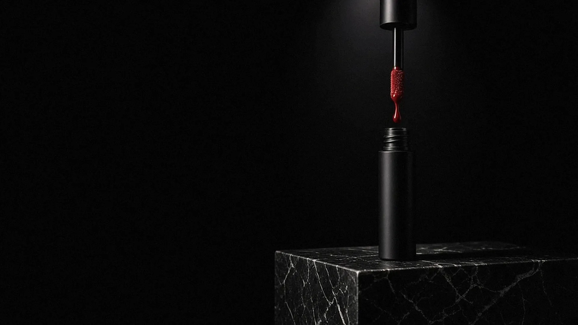 Tiub hitam dengan applicator merah di atas blok marmar gelap